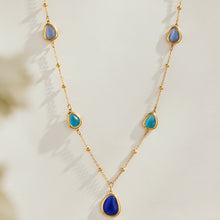 Gold-tone necklace with blue cat eye stones and teardrop pendant detail