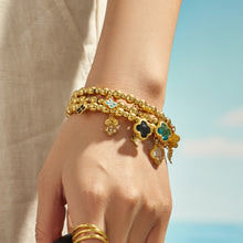 Blue clover charm bracelet styled on a model wrist with a gold beaded chain