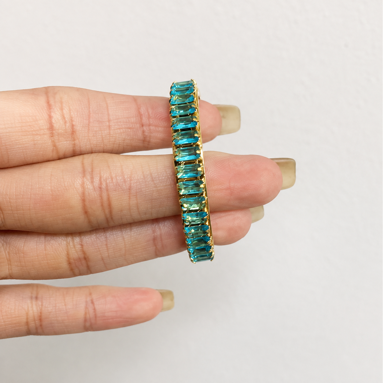 Hand-held blue cubic zirconia C-shaped hoop earrings with gold-tone 316L stainless steel