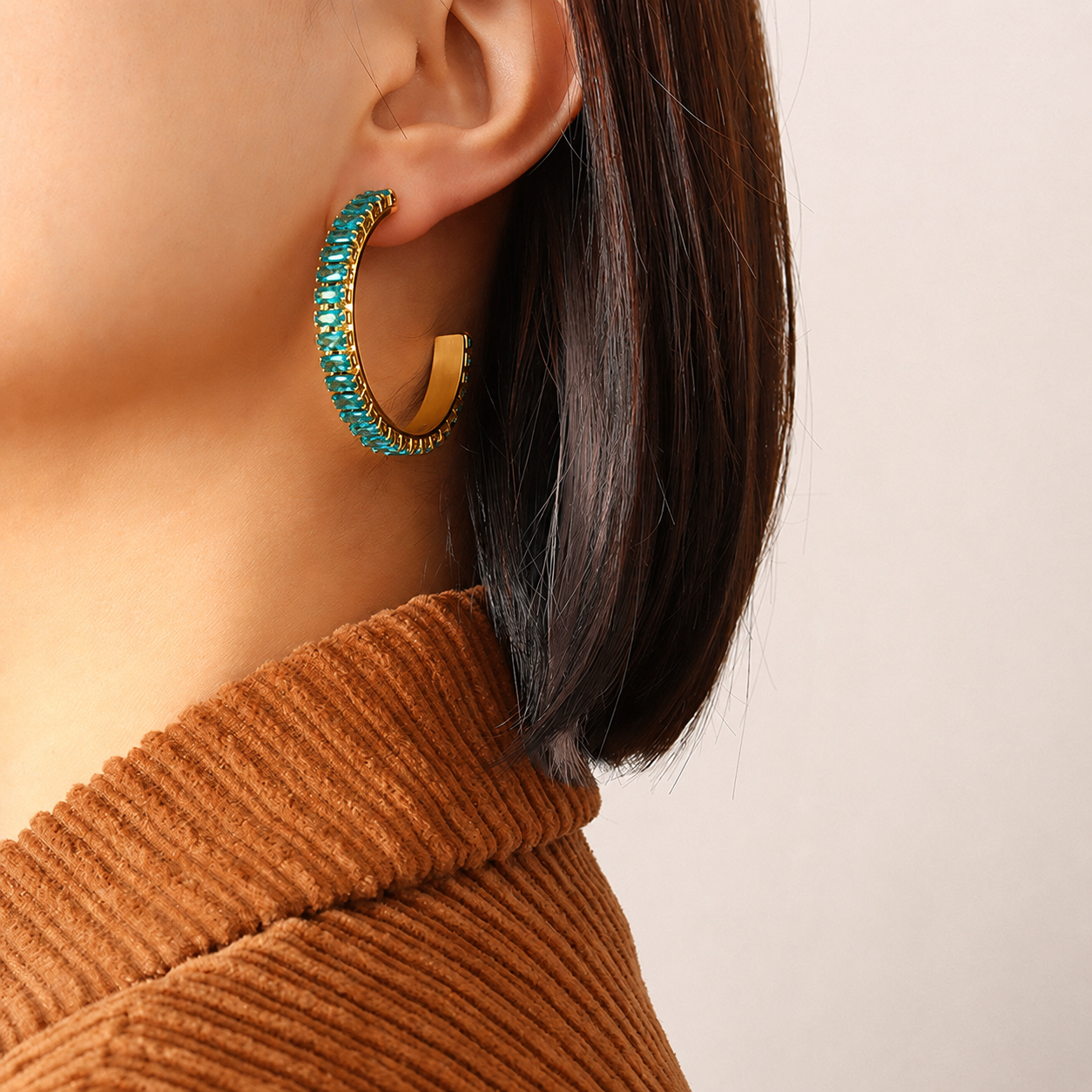 Model wearing blue cubic zirconia C-shaped hoop earrings