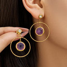 Model wearing blue glass stone drop earrings with twisted gold-tone hoop