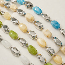 Blue white and polished steel resin jewelry strands arranged in a detailed flat lay