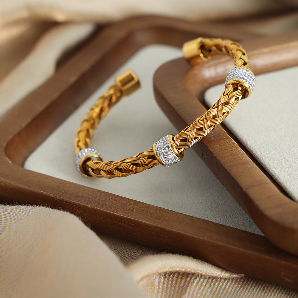 Braided stainless steel open bangle with clear cubic zirconia spacer details in a boutique display
