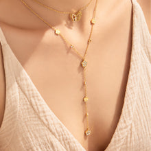 Close-up of gold-tone butterfly and floral Y necklaces worn on model