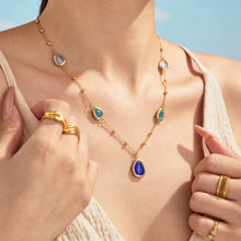 Gold-tone cat eye stone necklace with colorful geometric accents worn on model