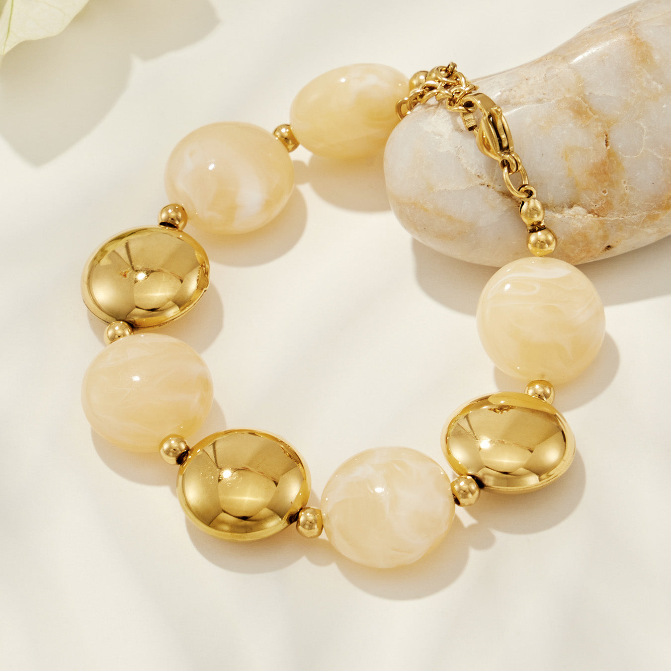 Close-up of a champagne resin bead bracelet with gold-tone accents on a clean product background.