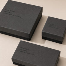 Close-up of charcoal gray jewelry boxes showing textured paper finish and black base