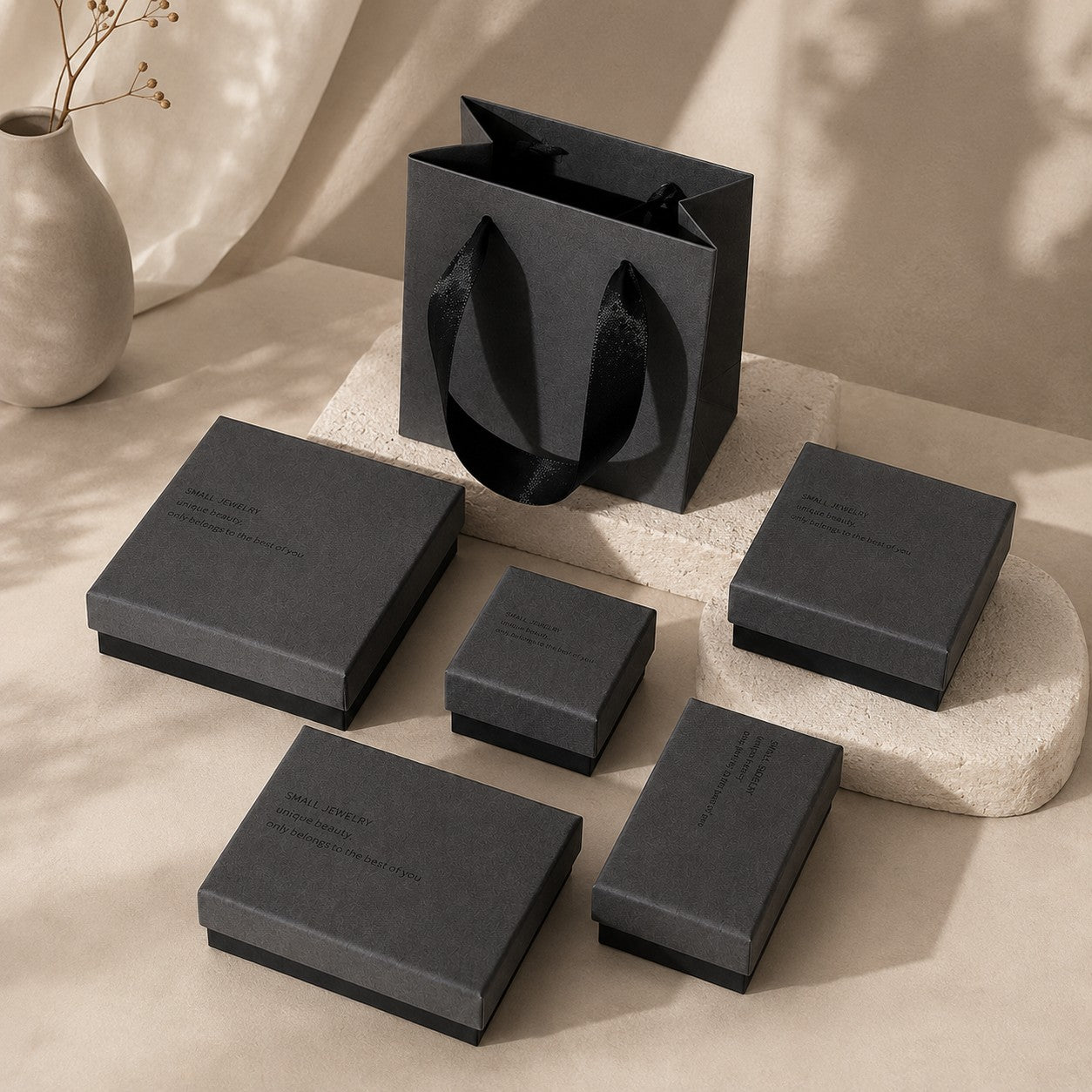 Charcoal gray jewelry gift boxes displayed on neutral stone stands for boutique packaging