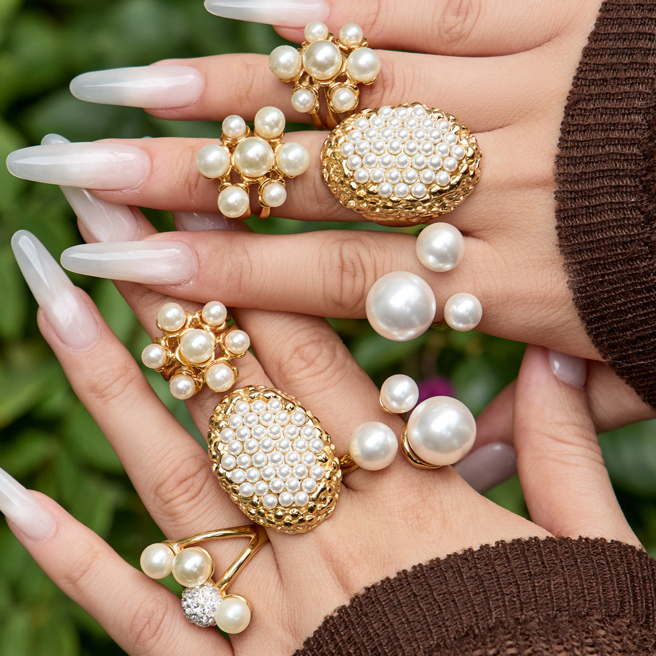 Chunky faux pearl statement rings styled with a brown knit sleeve