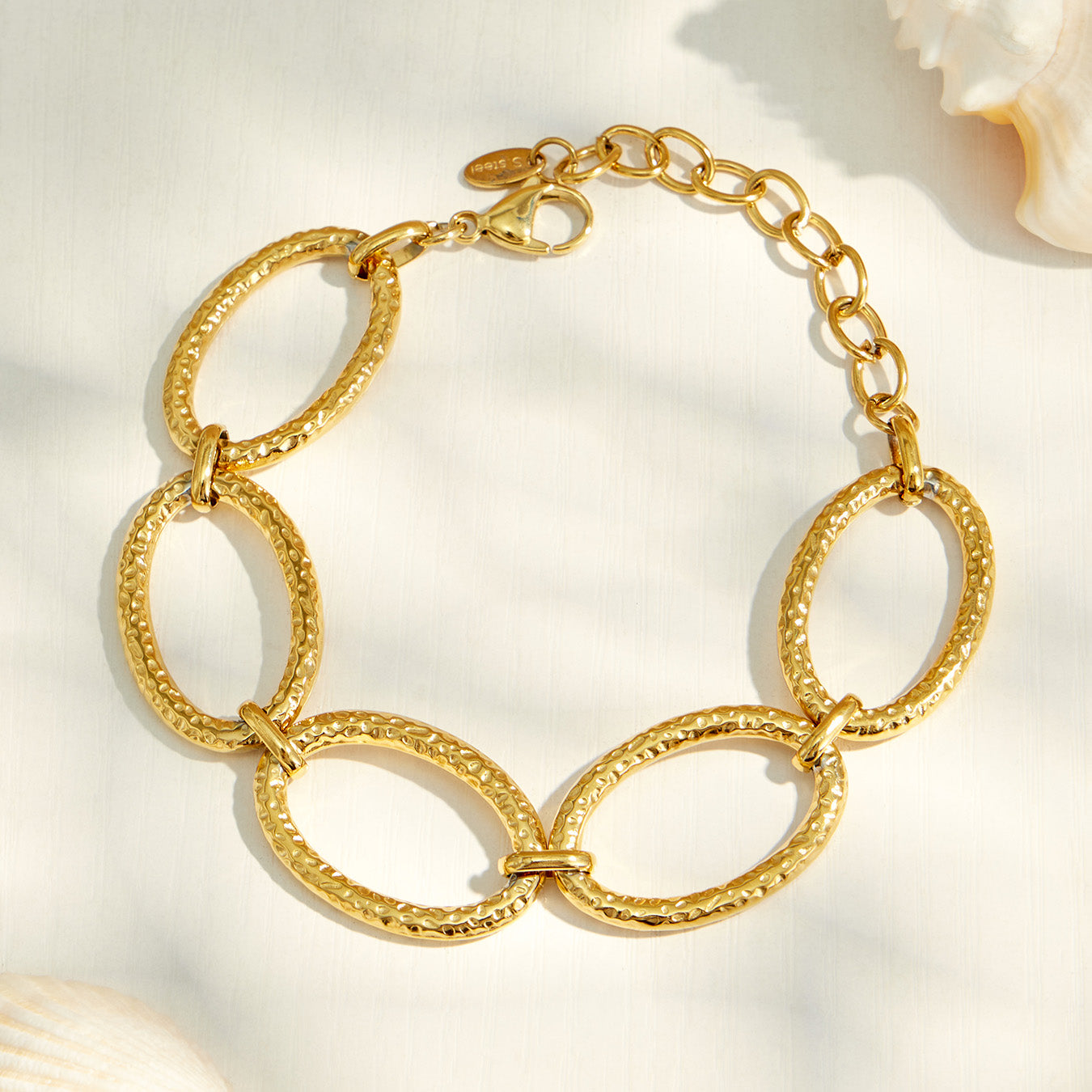 Chunky gold chain bracelet with oversized oval links worn with a black sleeve