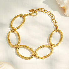 Chunky gold chain bracelet with oversized oval links worn with a black sleeve