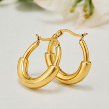 Pair of chunky gold C-shaped hoop earrings displayed on a neutral background