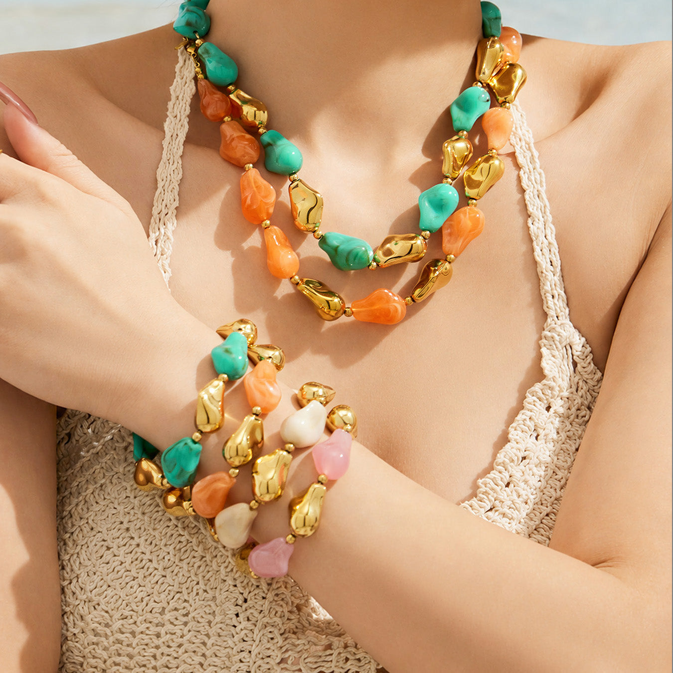 Model wearing a chunky green and orange resin necklace with matching stacked bracelets
