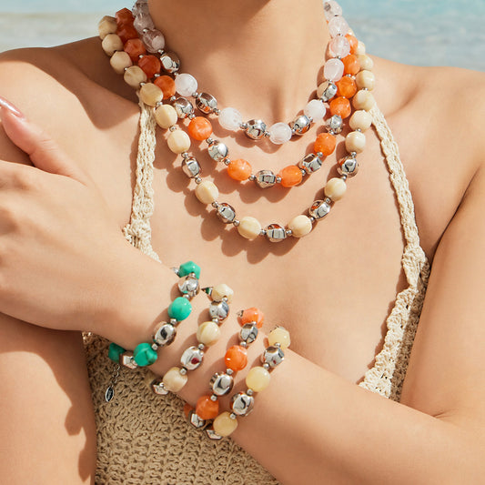 Model wearing layered colorful resin bead necklaces and matching bracelets in a statement summer styling look.