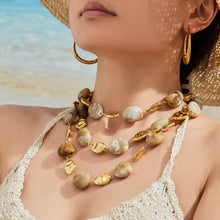 Model styling a chunky organic resin necklace in a layered statement jewelry look