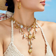 Coastal shell and starfish charm necklace styled on model for a layered summer look