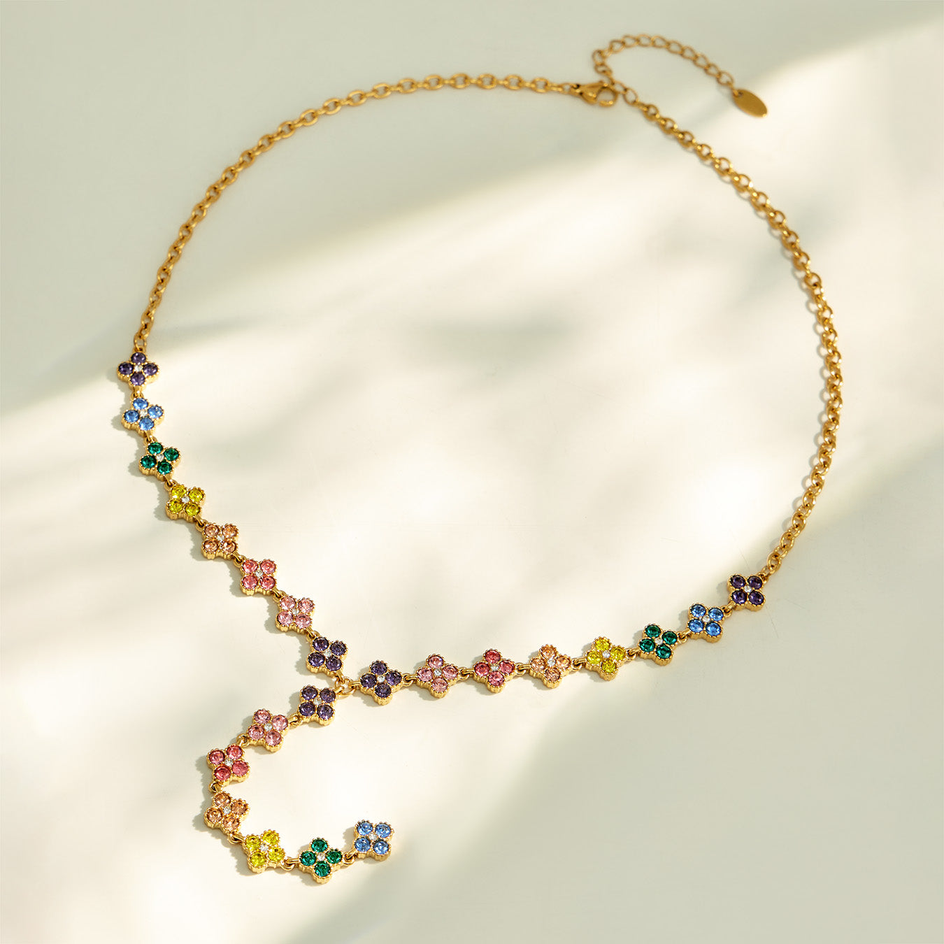 Colorful floral lariat necklace arranged in a circular flat lay on neutral fabric