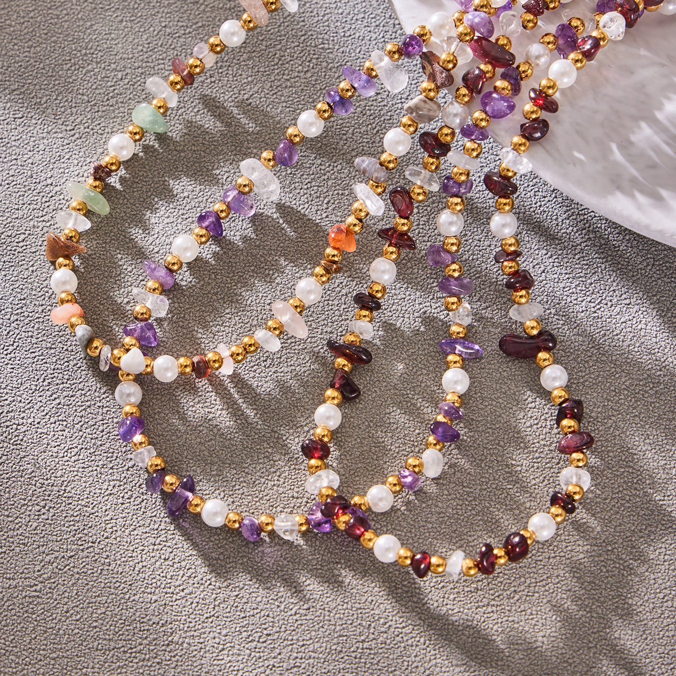 Colorful layered natural stone necklace arranged on softly draped gray fabric