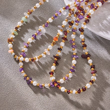 Colorful layered natural stone necklace arranged on softly draped gray fabric