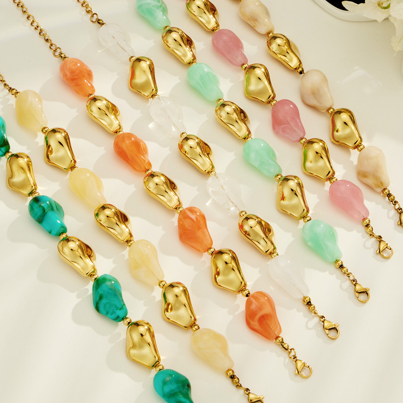 Colorful organic resin jewelry variants arranged in rows with sculptural gold-tone connector details