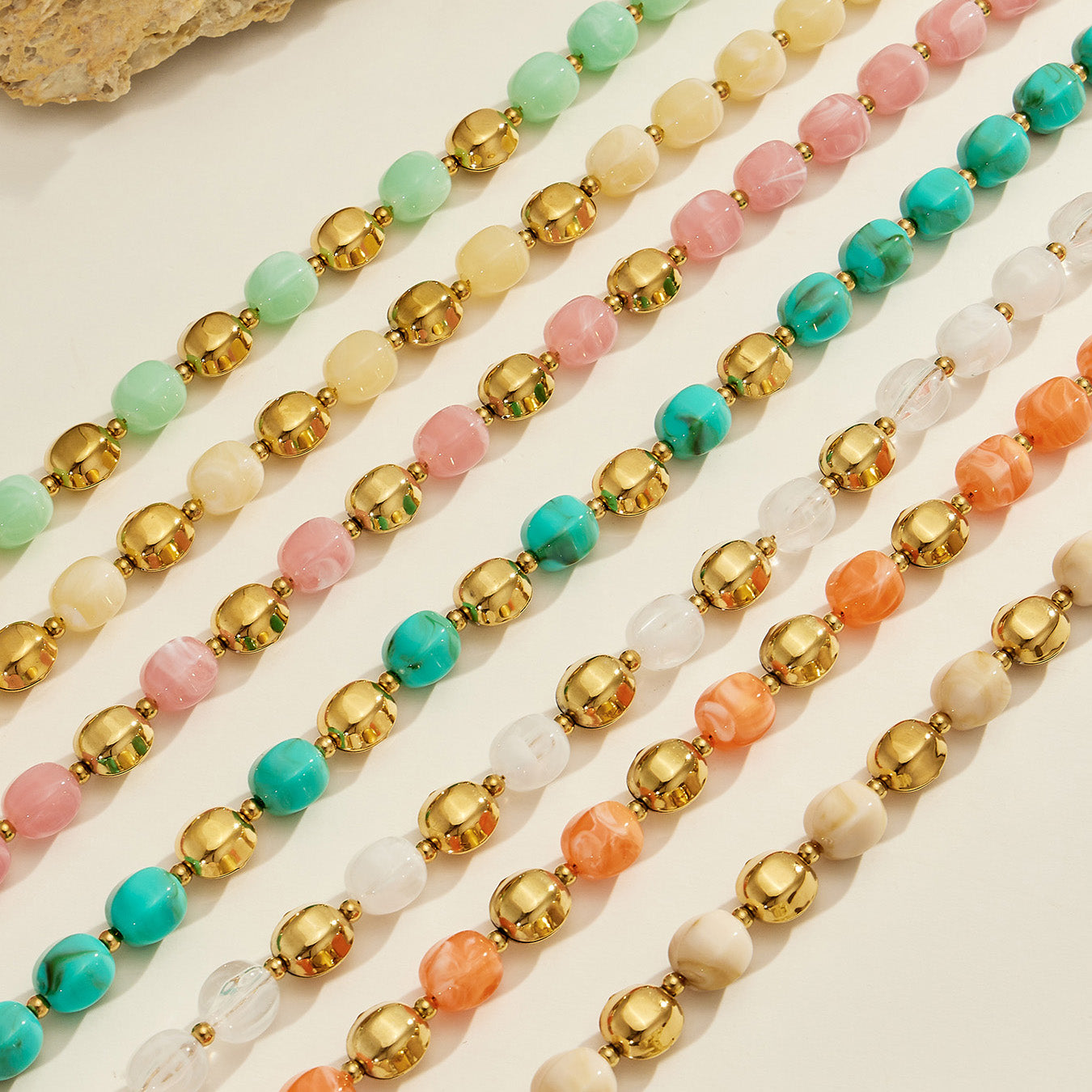 Diagonal flat lay of colorful resin bead jewelry strands showing multiple coordinated color options.