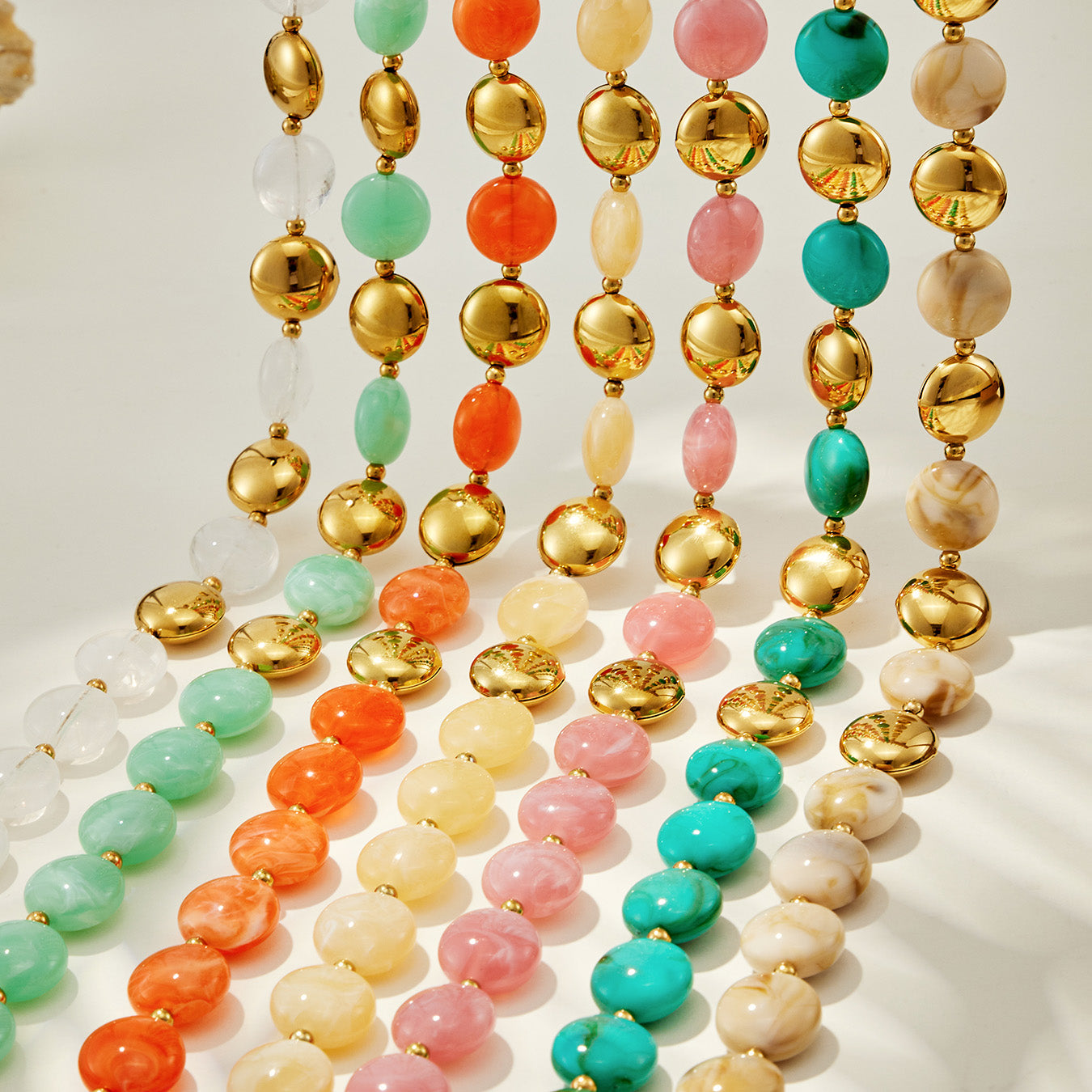 Flat lay of colorful resin bead strands in assorted tones used in bracelet and necklace jewelry designs.