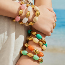 Close-up of colorful resin bead bracelets with gold-tone accents stacked on a model's wrists