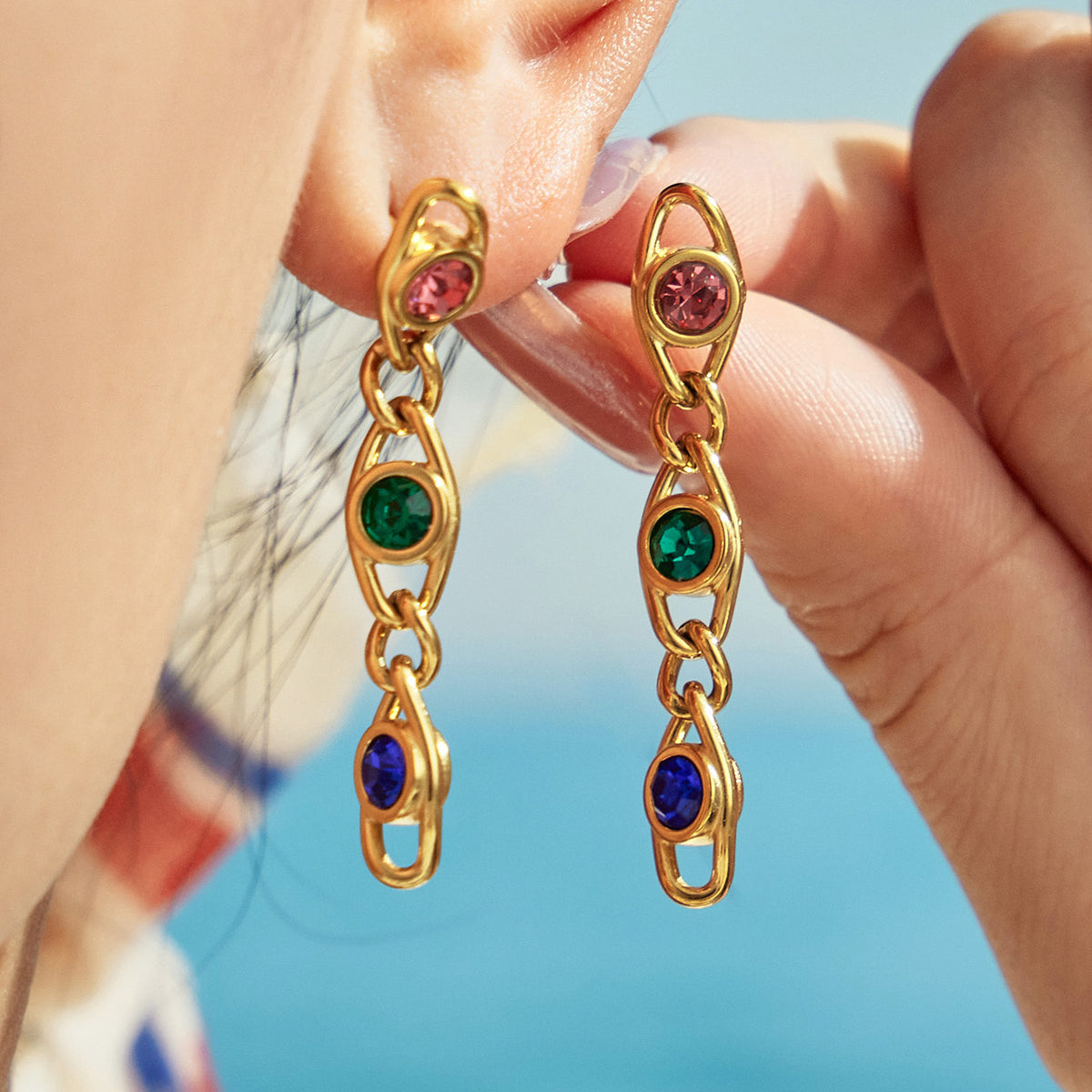 Colorful zircon drop earrings worn on ear and held in hand