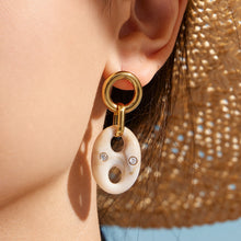Close-up of a cream resin link drop earring worn by a model
