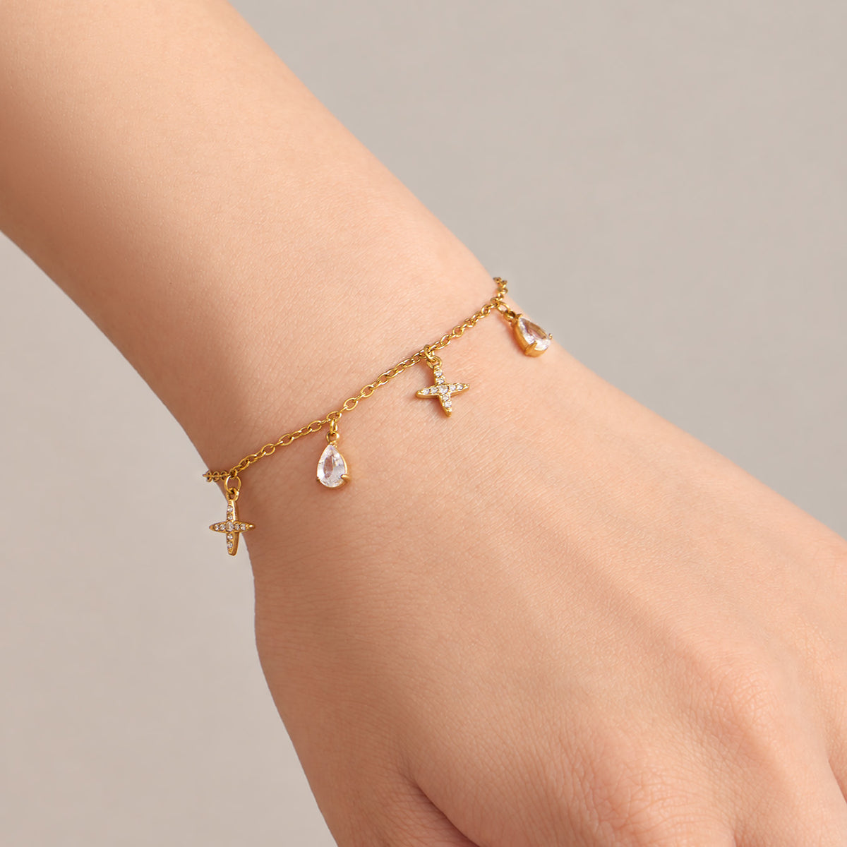 Cross and teardrop zircon charm bracelet worn on wrist