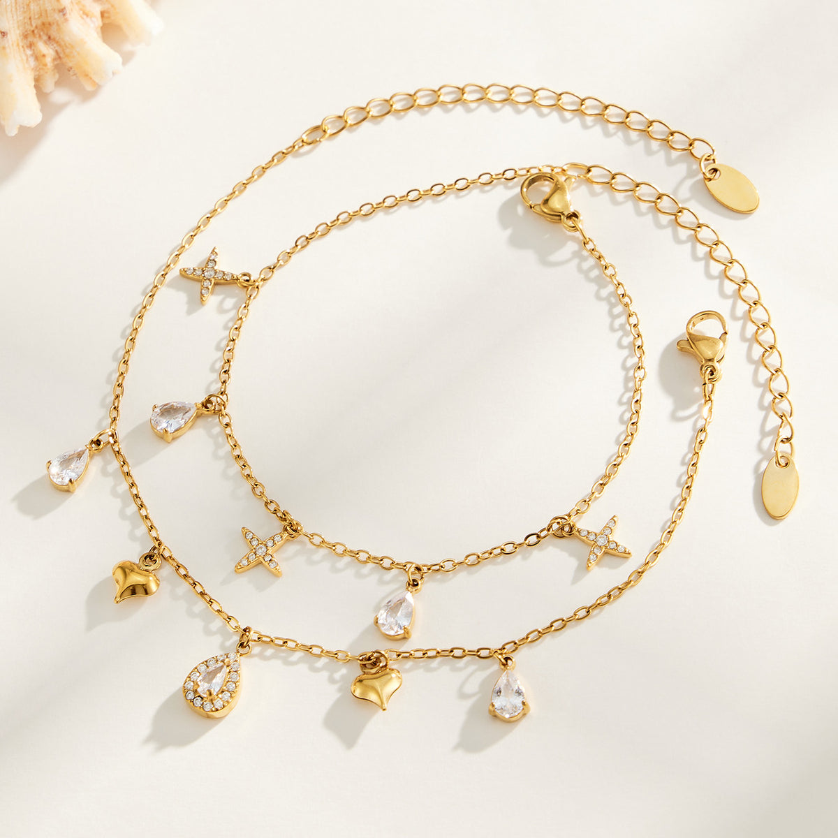 Gold-tone cross and heart charm bracelets with teardrop zircon details