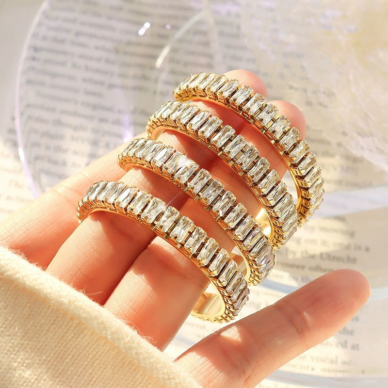 Multiple C-shaped cubic zirconia hoop earrings displayed in clear and colored stone styles