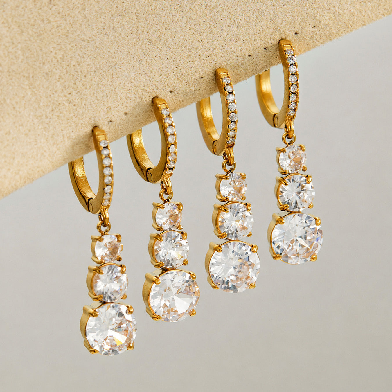 Multiple cubic zirconia droplet earrings displayed with gold hoop settings