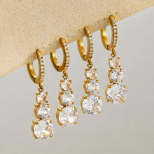 Multiple cubic zirconia droplet earrings displayed with gold hoop settings