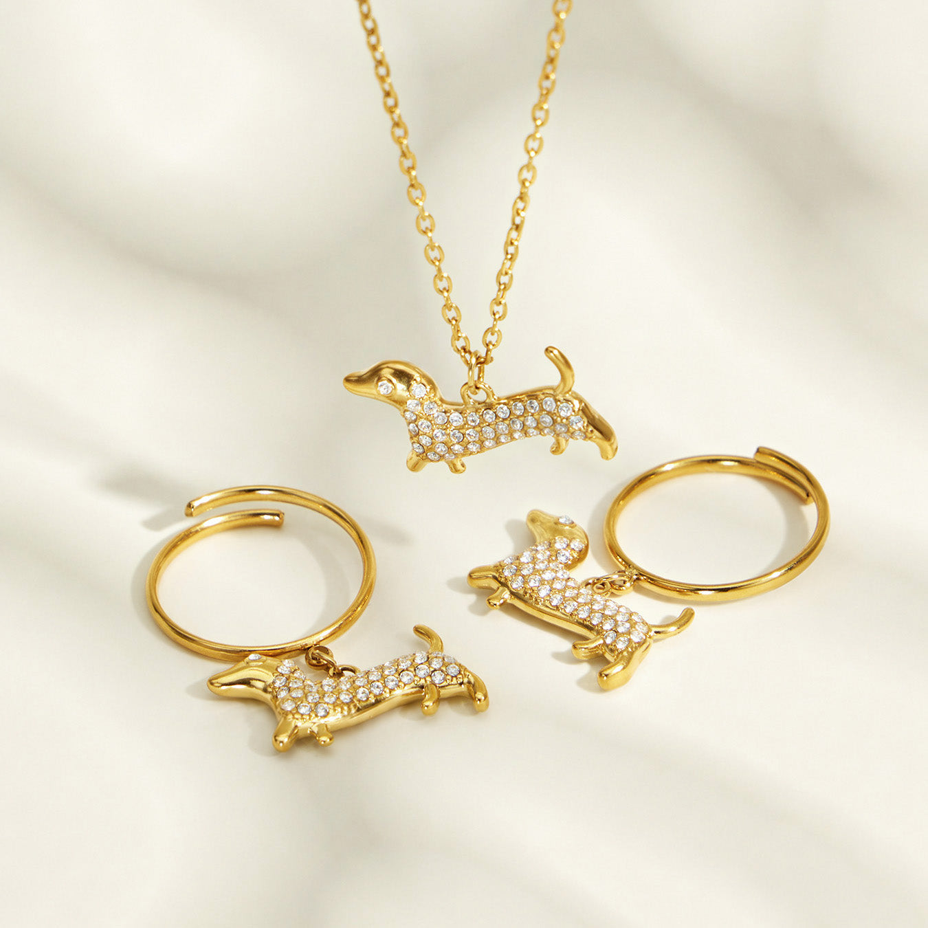 Model in a straw hat wearing layered gold necklaces with a dachshund zircon pendant