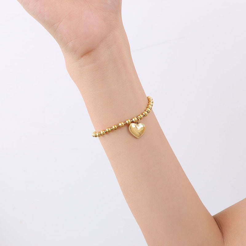 Dainty gold heart charm bracelet styled on the wrist