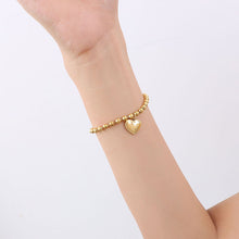 Dainty gold heart charm bracelet styled on the wrist