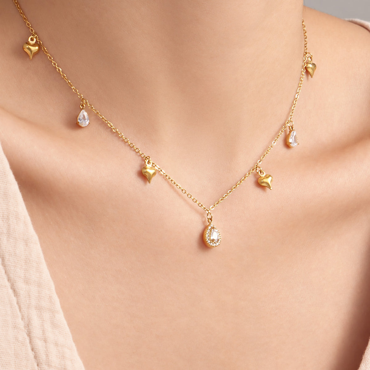 Dainty gold heart necklace with teardrop zircon charms worn at the collarbone