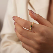 Model wearing a dainty gold-tone ring with a single green heart zircon stone