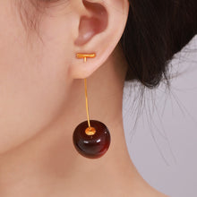 Side view of a model wearing dark burgundy resin cherry earrings