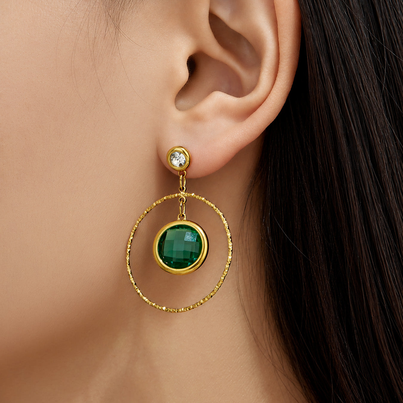 Model wearing dark green glass stone drop earrings with gold twisted hoop