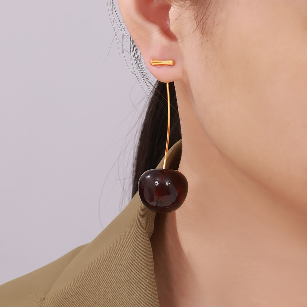 Model wearing deep red gradient cherry dangle earrings with long stems