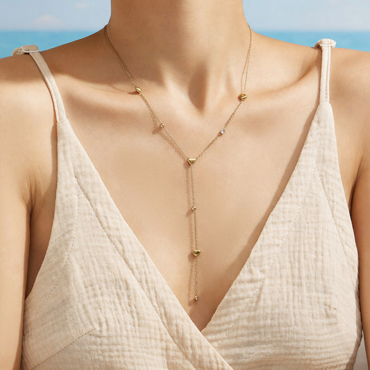 Model wearing a delicate gold heart lariat necklace with an elongated Y-shaped drop