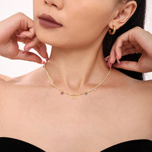 Close-up of a delicate layered beaded necklace styled on a model with colorful stone details
