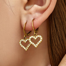 Side view of double heart drop earrings worn on the ear