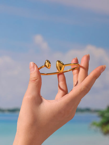 double heart open bangle model front view - holding gold heart bangle in hand