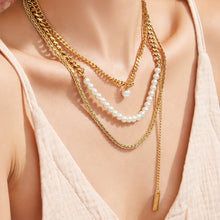 Model wearing a double-layer gold necklace with delicate faux pearl accents
