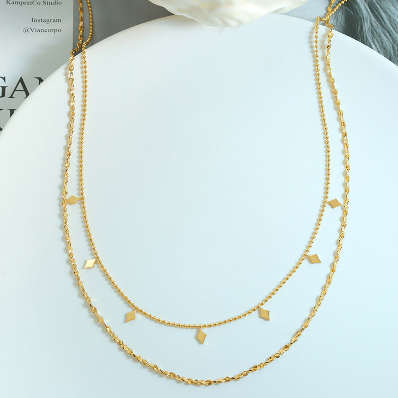 Flat lay of a gold-tone double-layer stainless steel necklace with geometric charm details
