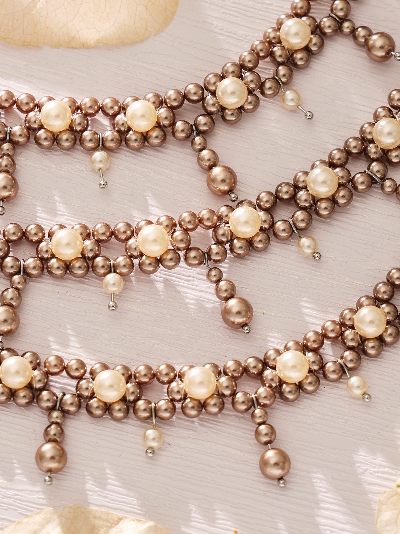 Close-up of double-row shell bead bracelets with dangling pearl-style accents