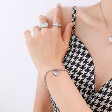 Model wearing an engraved heart charm bracelet with a beaded chain